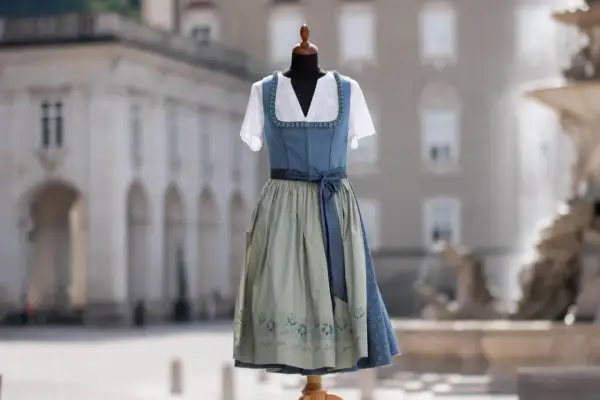 Blauer Dirndl mit hellgrünem Rock und Blumenmuster. Die dirndl farben bedeutung kann von Region zu Region variieren, aber Blau steht oft für Treue.