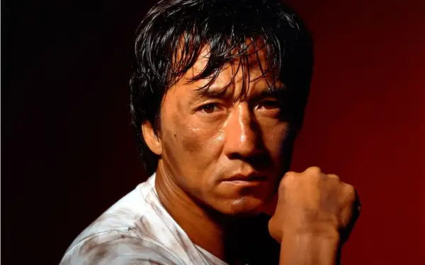 Jackie Chan, med svettig panna och en knuten näve, redo för action i sina filmer.