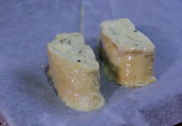 Dos trozos de pan empapados en huevo y leche, listos para hornearse como torrijas.