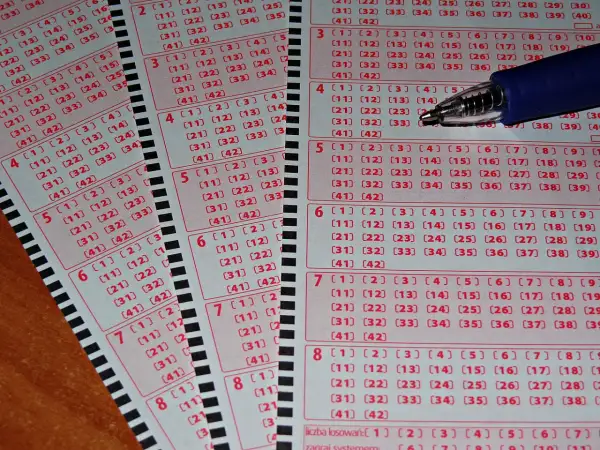 Kupony lotto i pytanie: czy wygrana w Jaka to melodia jest opodatkowana tak samo jak w lotto? Długopis nad polami do zaznaczenia liczb.
