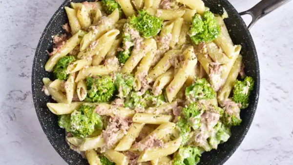 Penne z tuńczykiem i brokułami w kremowym sosie śmietanowo-serowym, przygotowane w czarnej patelni.