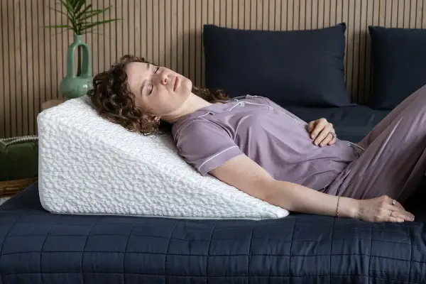 Woman sleeping on a wedge pillow. Learn how to make memory foam pillow expand faster for ultimate comfort.