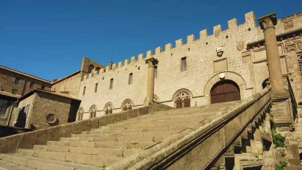 Imponente scalinata conduce al Palazzo dei Papi, parte del duomo di Viterbo, con finestre gotiche e merlature.