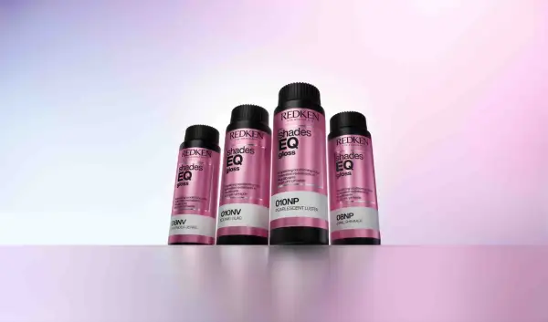 Cuatro botellas de baño de brillo para el pelo Redken Shades EQ Gloss en tonos perlados y lilas, listas para dar un acabado radiante.
