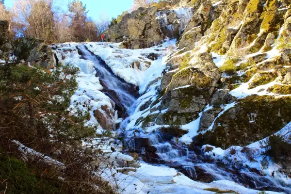 Cascada helada en el abedular de Canencia, con escaladores ascendiendo por el hielo y la roca.
