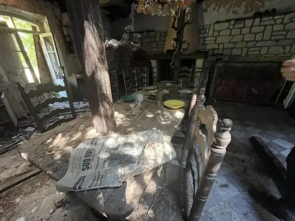 Table dressée dans une maison abandonnée, vestige d'un urbex à Bordeaux. Lumière filtrant par la fenêtre, poussière sur les assiettes.