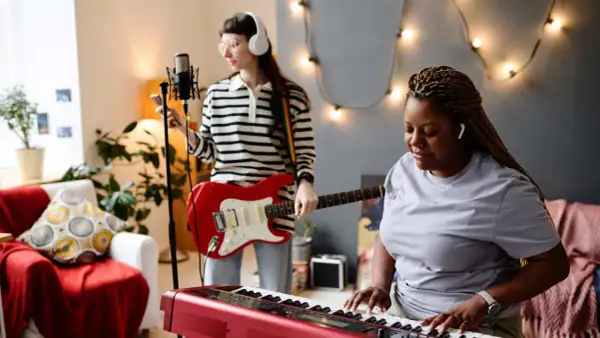 Dwie kobiety tworzą muzykę: jedna gra na keyboardzie, druga na gitarze. Słychać idealną harmonię instrumentów.