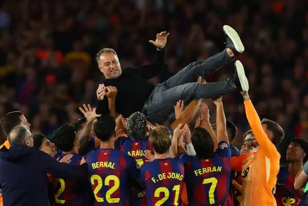 Piłkarze FC Barcelona 22/23 unoszą trenera Xaviego w geście radości po wygranym meczu.