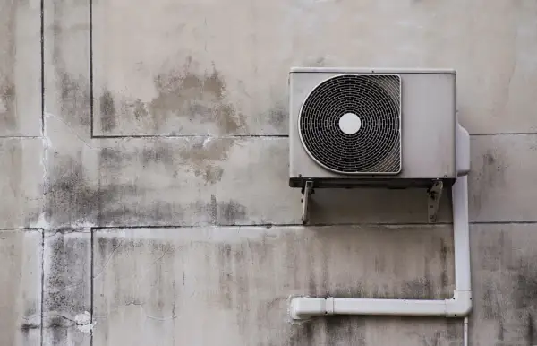 Unité extérieure d'une pompe à chaleur installée sur un mur en béton. Le système est prêt à fonctionner.