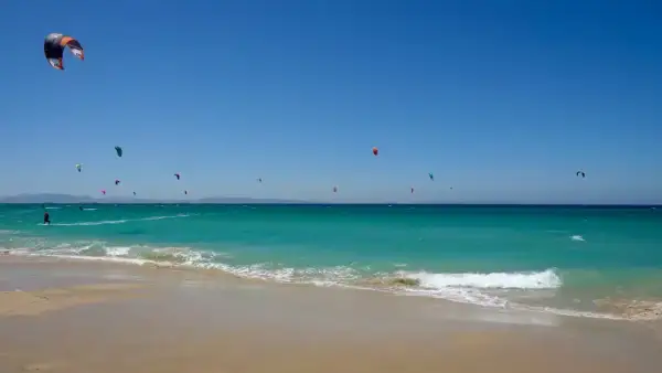 El levante en Tarifa impulsa a numerosos kitesurfistas sobre aguas turquesas. Un día perfecto para disfrutar del mar y el viento.