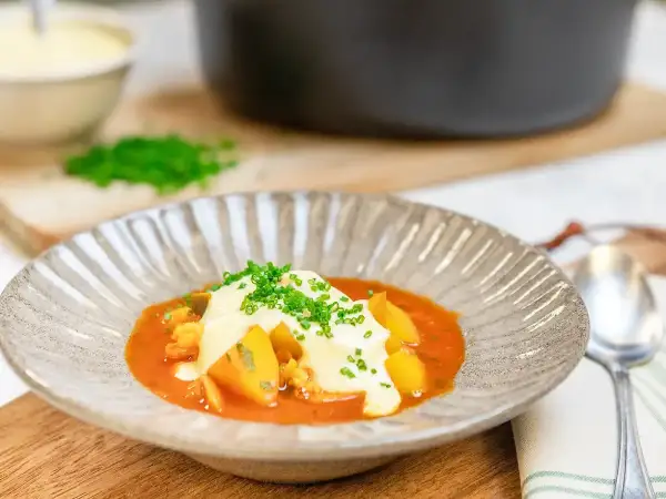 En vällagad fisksoppa med saffran, toppad med krutonger och färska örter. Serveras i en vacker skål med en sked bredvid.