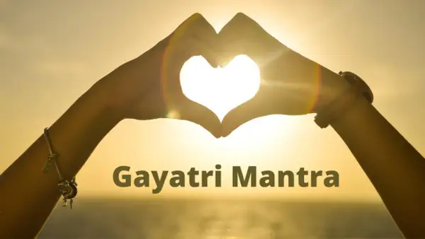 Manos forman un corazón al atardecer, iluminando el significado del Gayatri Mantra.
