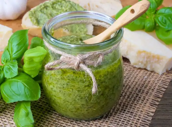 Frisches Pesto im Glas, zubereitet mit dem Thermomix, daneben Basilikum, Parmesan und Brot.