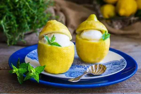 Delizioso gelato al limone servito in limoni svuotati, guarnito con menta fresca. Un'idea rinfrescante preparata con una gelatiera.