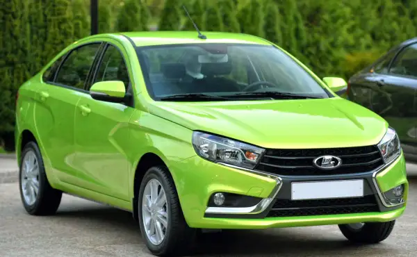 En ljusgrön Lada Vesta står parkerad utomhus.