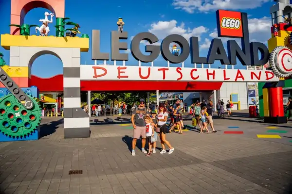 Rodzina pozuje przed wejściem do Lego Land Deutschland. Kolorowe klocki i wielkie logo zapraszają do świata zabawy.