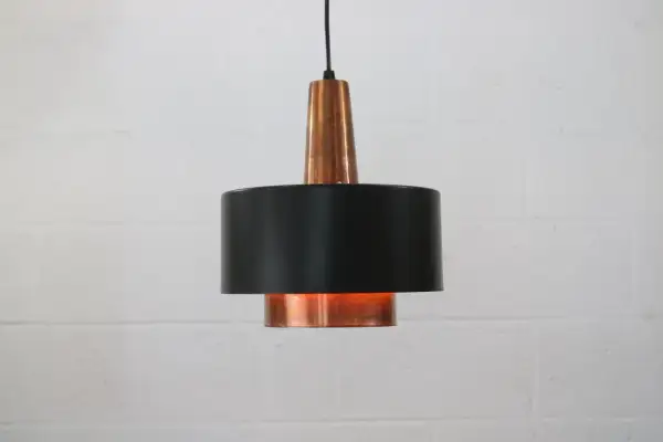 Stylowa lampa sufitowa z miedzi i czarnego metalu, dodająca ciepła wnętrzu.
