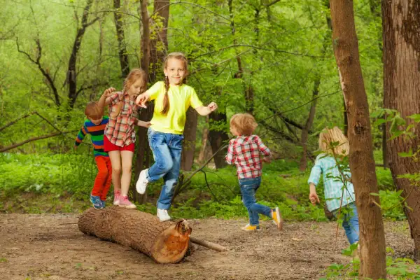 Niños jugando en un tronco, practicando el equilibrio. ¡Una escena de diversión y desarrollo para el equilibrio en niños de 1 a 2 años!
