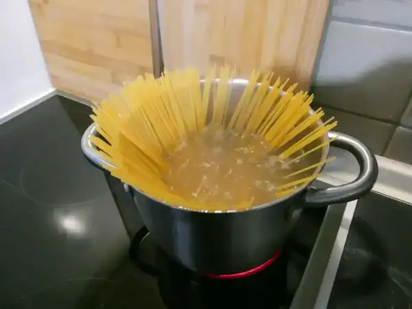 Długi makaron spaghetti gotuje się w garnku z wrzącą wodą. Czas gotowania jest kluczowy, by był idealnie al dente.