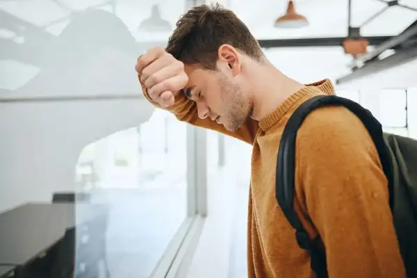 Zmartwiony uczeń z plecakiem opiera się o okno. Czy uczeń nieklasyfikowany jest promowany?
