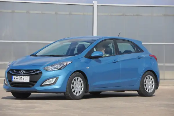 Niebieski Hyundai i30, gotowy do jazdy dziennej. Kierowca w okularach siedzi za kierownicą.