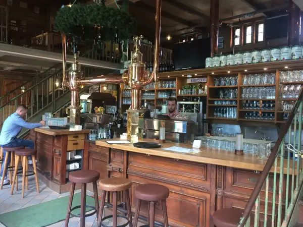 Gemütliche Atmosphäre im Brauhaus Spandau. Ein Mann sitzt am Tresen, hinter ihm Regale voller Gläser und Bierfässer.