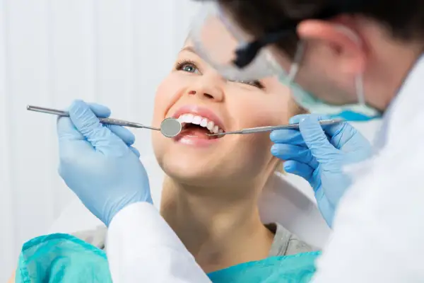Uśmiechnięta pacjentka u dentysty. Zastanawiasz się nad lakowaniem zębów? Skutki uboczne są rzadkie, ale warto wiedzieć.