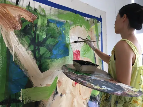 Lucy Liu artwork in progress: the artist adds bold strokes of black paint to a vibrant, abstract canvas, her palette ready for more color.