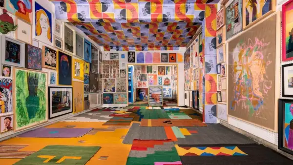 Vibrant art fills a room, from the ceiling posters to the floor rugs, showcasing the diverse creativity of Mexico City Art Week.