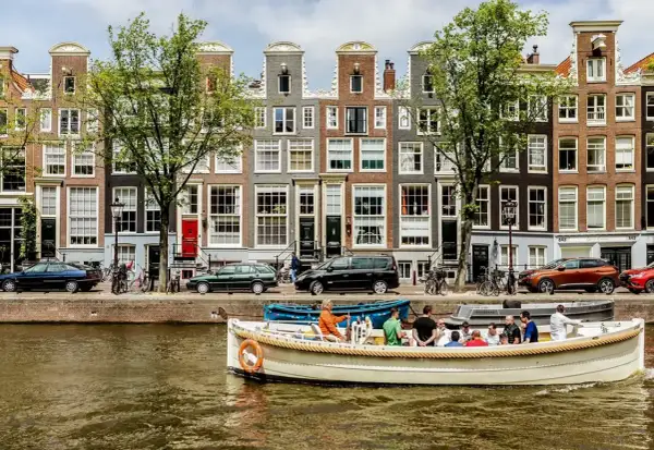 En båttur på kanalerna är ett måste i Amsterdam. Vackra hus och träd kantar vattnet.