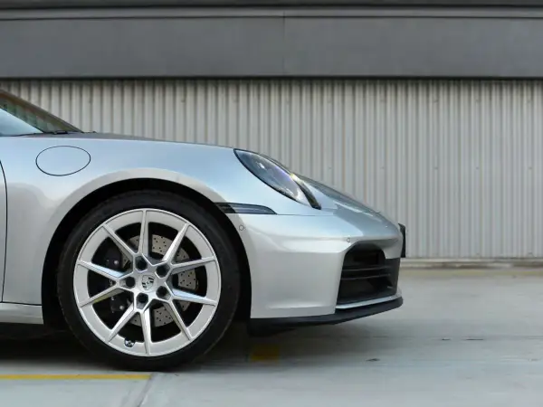 Srebrny Porsche 911 Carrera 4S z felgami i zaciskami hamulcowymi.
