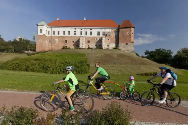 Rodzina na rowerach odkrywa sandomierskie trasy rowerowe z widokiem na zamek.