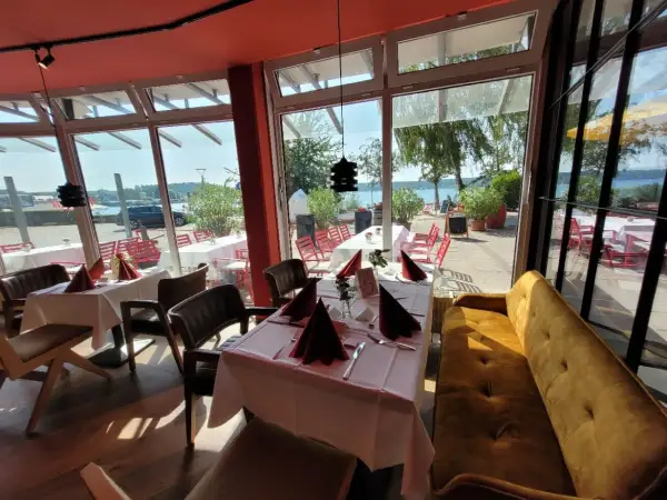 Gemütliche Tische mit rotem Stoff und Blick aufs Wasser – hier könnte das beste Restaurant in Waren sein.