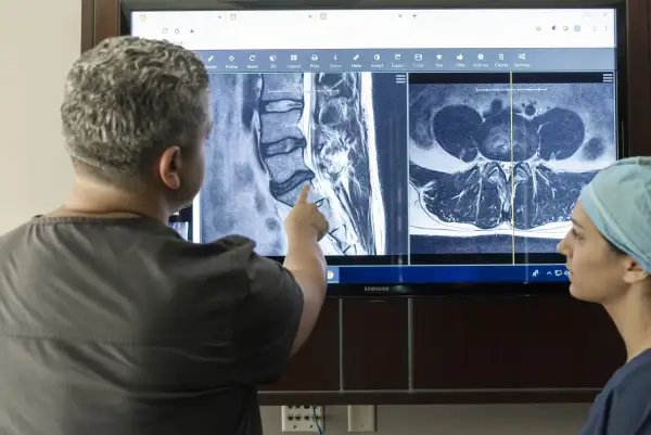 Läkare diskuterar MR-bilder av ryggraden, potentiellt relaterade till diskbråck i nacken operation risker.