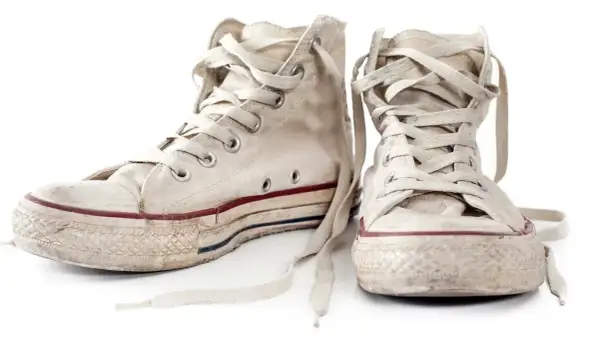 Zwei abgetragene, weiße Chucks mit Schnürsenkeln, bereit zum Chucks waschen.