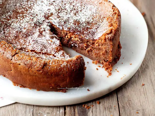 Torta soffice e golosa, uno dei tanti dolci con cioccolato al latte, spolverata di zucchero a velo su un piatto di marmo.