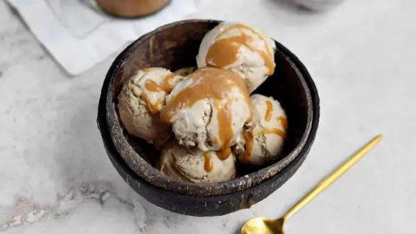 Schüssel mit erdnussbutter eis, beträufelt mit Karamellsauce. Ein goldener Löffel liegt daneben.