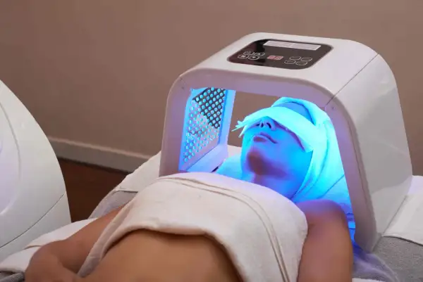 Une femme reçoit un traitement de luminothérapie visage, profitant des bienfaits de cette technologie pour une peau éclatante.