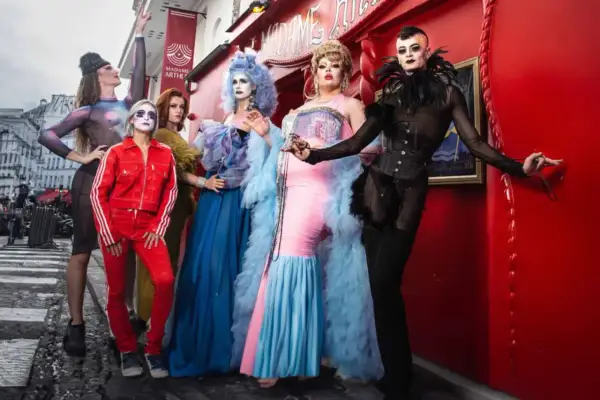 Cinq artistes de drag queen posent devant le cabaret Madame Arthur à Paris, prêts pour un spectacle flamboyant.