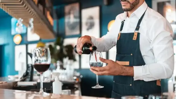Doświadczony sommelier wina nalewa czerwone wino do kieliszka w eleganckiej restauracji.