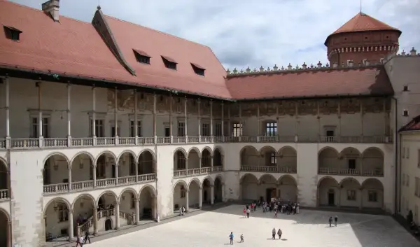 Dziedziniec zamku królewskiego na Wawelu, z arkadowymi krużgankami i wieżą. Ciekawostki o historii tego miejsca czekają na odkrycie.