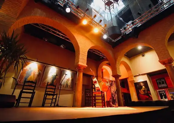 Escenario listo para la gracia flamenca. Sillas, guitarras y cuadros evocan la pasión del arte.