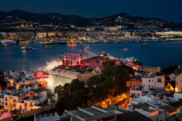 Concerto sul bastione di Dalt Vila, Ibiza, con la baia illuminata e le luci della città. Un evento indimenticabile per chi ama la musica e la magia di IMS Ibiza.