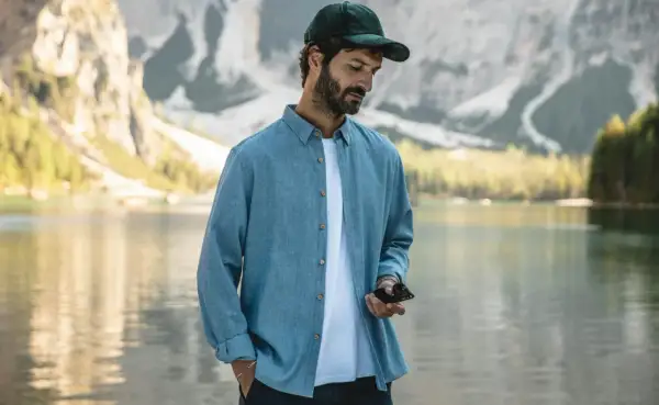 Un homme porte une chemise bleue décontractée, dont la matière légère est parfaite pour une journée au bord du lac.