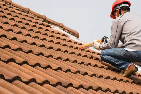 Handwerker repariert die Dachrinne mit einer Kartuschenpistole.