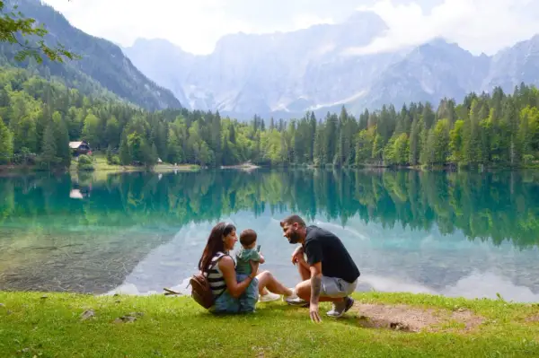 Familia disfrutando del lago turquesa y montañas, un lugar idílico que ver en Eslovenia.