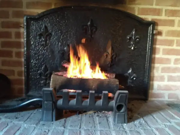 Un feu crépite dans une cheminée en briques, avec un système discret pour récupérer la chaleur d'un conduit de cheminée.