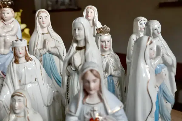 Eine Sammlung von Marienfiguren, die an das maria geburt datum erinnern. Die Figuren tragen weiße Gewänder und einige haben Kronen.