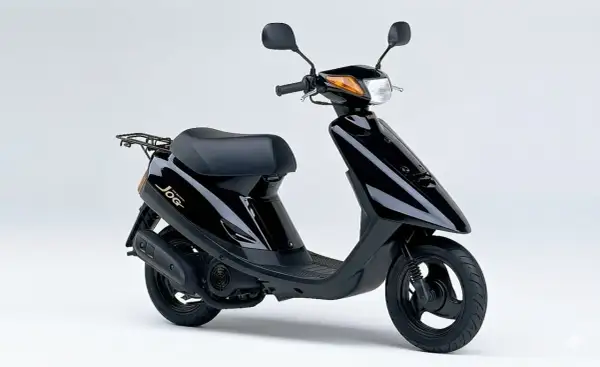 Ciclomotor negro Yamaha Jog, un clásico de los ciclomotores de los 90, con asiento y parrilla trasera.