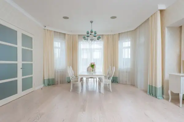 Eleganckie firanki w wykuszu dodają uroku wnętrzu. Jasne zasłony pięknie komponują się z białymi meblami i jasną podłogą.